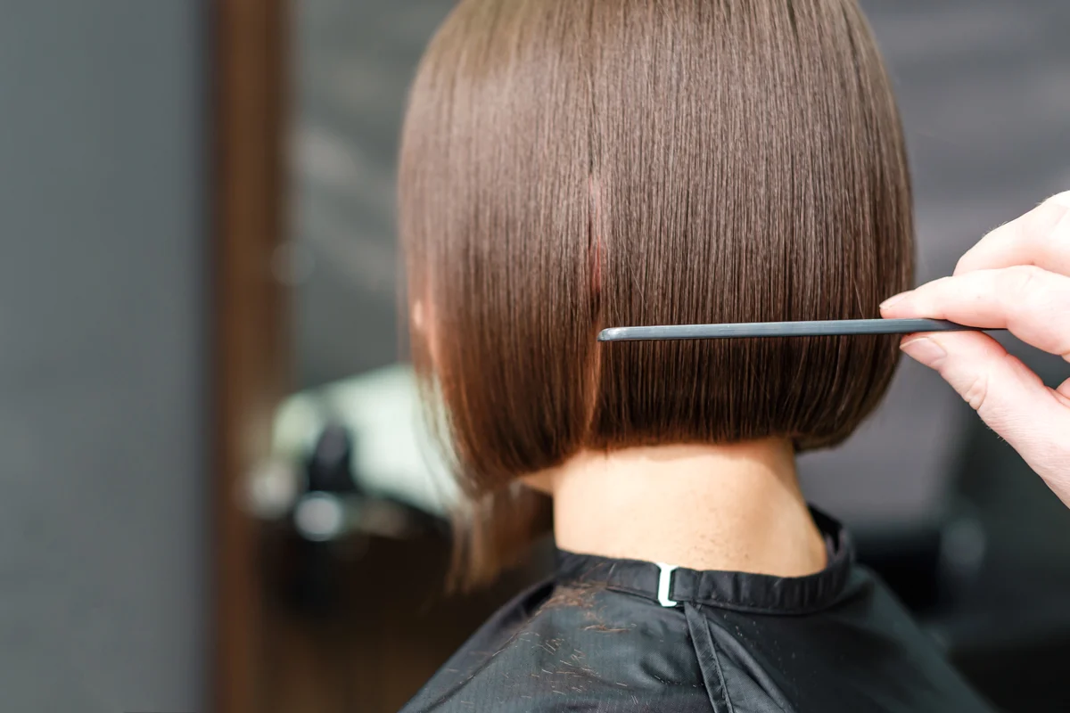 Friseur arbeitet am Haar einer Kundin